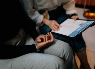 Two businesswomen look over a resume on a clipboard