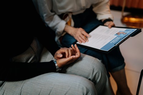 Two businesswomen look over a resume on a clipboard